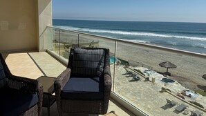 A balcony with wicker furniture overlooking a beach. - Stunning, Relaxing Beachfront With Endless Activities & Enjoyment (Rosarito)