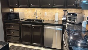 A modern kitchen with dark cabinetry, a stainless steel dishwasher, a built-in microwave, a toaster, and a blender. - Stunning, Relaxing Beachfront With Endless Activities & Enjoyment (Rosarito)