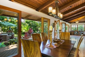 An indoor dining area with wooden furniture, large windows, and a ceiling with exposed beams.