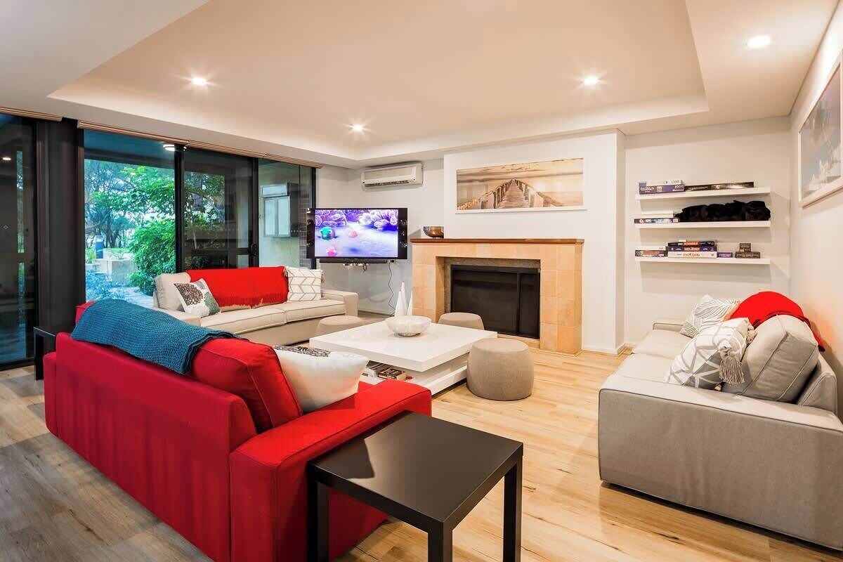 Un salon moderne avec un canapé rouge, un canapé gris, une table basse et un téléviseur.