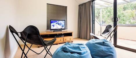 A modern living room with a television, two bean bag chairs, and a sliding glass door to a balcony.