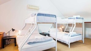 A room with two bunk beds, a bedside table with a lamp, and a wall-mounted heater. - Broadwater Bliss—Beachside Escape w/ Resort Perks (Broadwater)