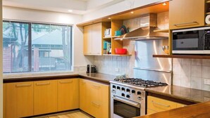 A kitchen with wooden cabinets, a gas stove, a microwave, and a window with blinds. - Broadwater Bliss—Beachside Escape w/ Resort Perks (Broadwater)