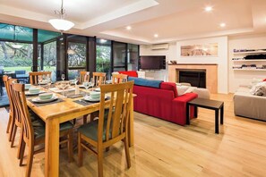 A modern living room with a dining area, a red sofa, and a fireplace.