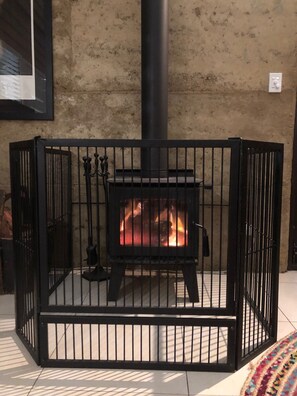 Een zwarte metalen kachel met een vuur erin, omgeven door een zwart metalen hek.