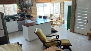 Amplia sala de estar con techo de madera, cocina equipada con electrodomésticos modernos y comedor con una isla grande.
