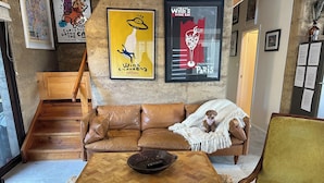 Un espacio de sala acogedor con un sofá de cuero marrón, una mesa de centro de madera y un sillón amarillo.