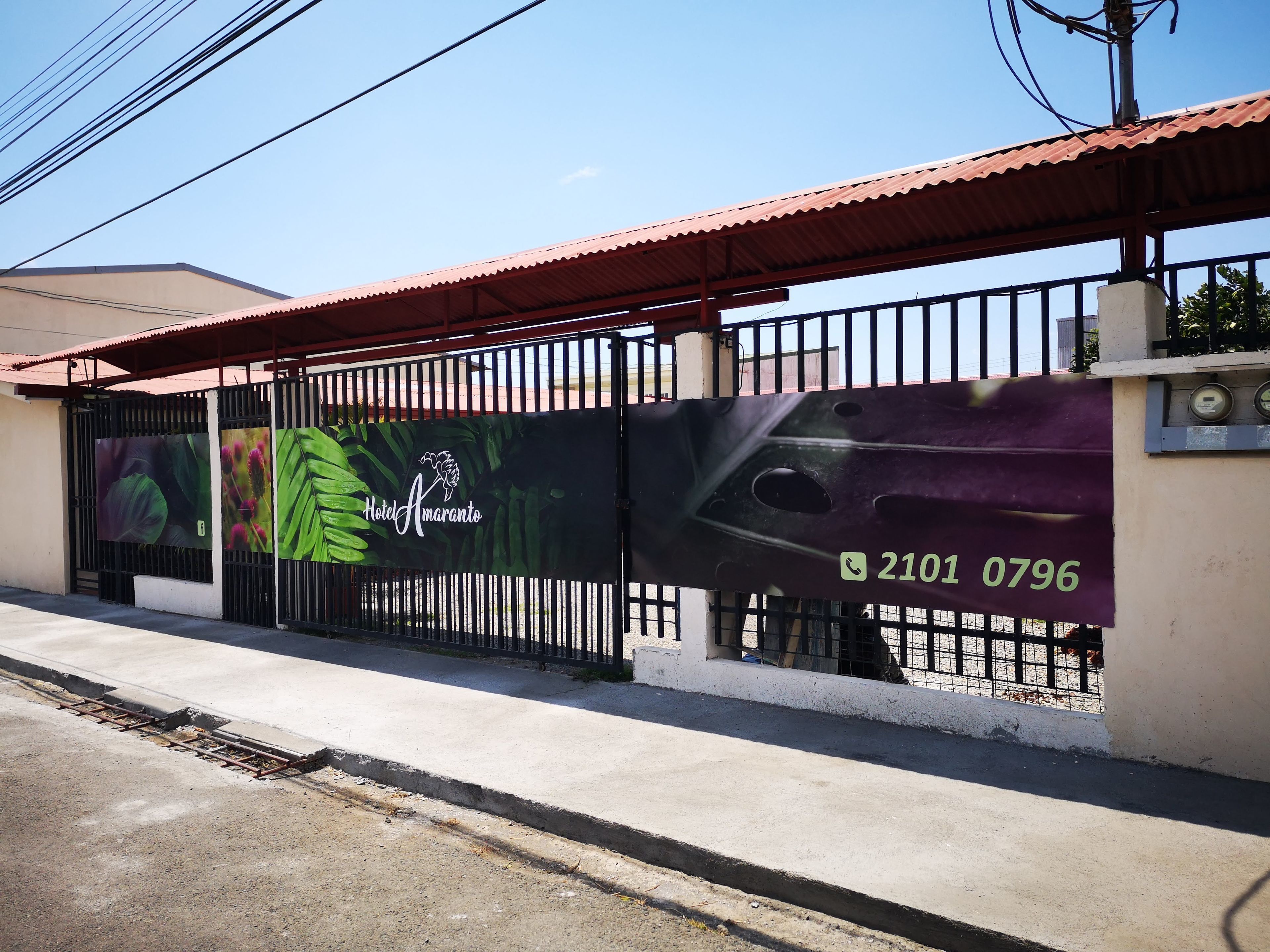 Entrada cerrada al Hotel Amaranto, con el número de contacto 2101 0796 mostrado en la puerta.
