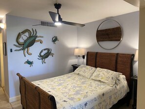 A bedroom with a bed, a ceiling fan, a wall-mounted lamp, and decorative wall art. - Beautiful Oceanfront Condo (St Thomas)