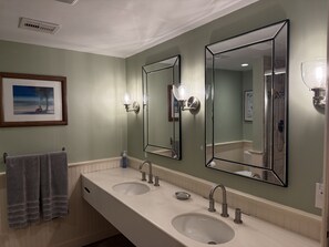 A bathroom with two sinks, a large mirror, and a towel rack. - Beautiful Oceanfront Condo (St Thomas)