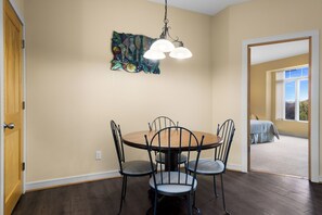 A dining area with a round table and four chairs, a hanging light fixture, and a wall-mounted artwork.