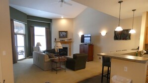 Un salon comprenant un canapé, un fauteuil et une table basse, une cheminée et un téléviseur.