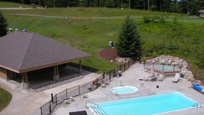 Une piscine dotée de chaises longues et d’un jacuzzi, le tout entouré d’une clôture et agrémenté d’un espace de détente abrité.