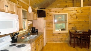 Cocina de cabaña de madera con estufa, fregadero y comedor.