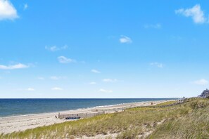 A beach with a fence, a building, and the ocean.