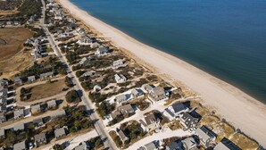 An aerial view of a coastal residential area with houses along the beachfront, a clear sky, and a calm sea. - Oceanside 1 -  East Sandwich waterfront cottage (Sandwich/East Sandwich)