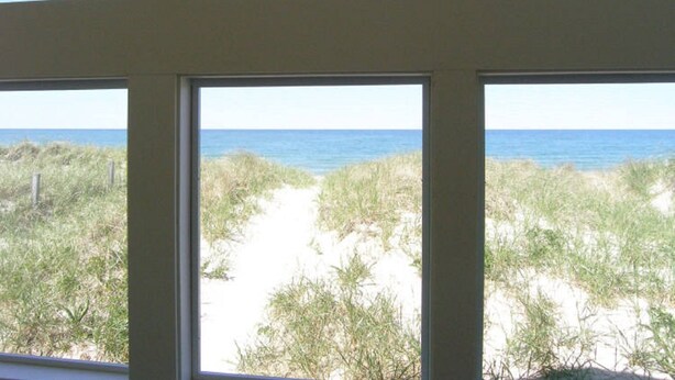 A view through a window with a beach and dunes in the background. - Oceanside 1 -  East Sandwich waterfront cottage (Sandwich/East Sandwich)