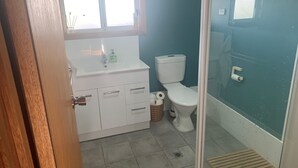 Et badeværelse med en hvid vask, toilet og bruseafsnit.