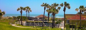 Ein Küsteneigentum mit einem Weg, der zu einem Gazebo führt, umgeben von Palmen und Blick auf das Meer.