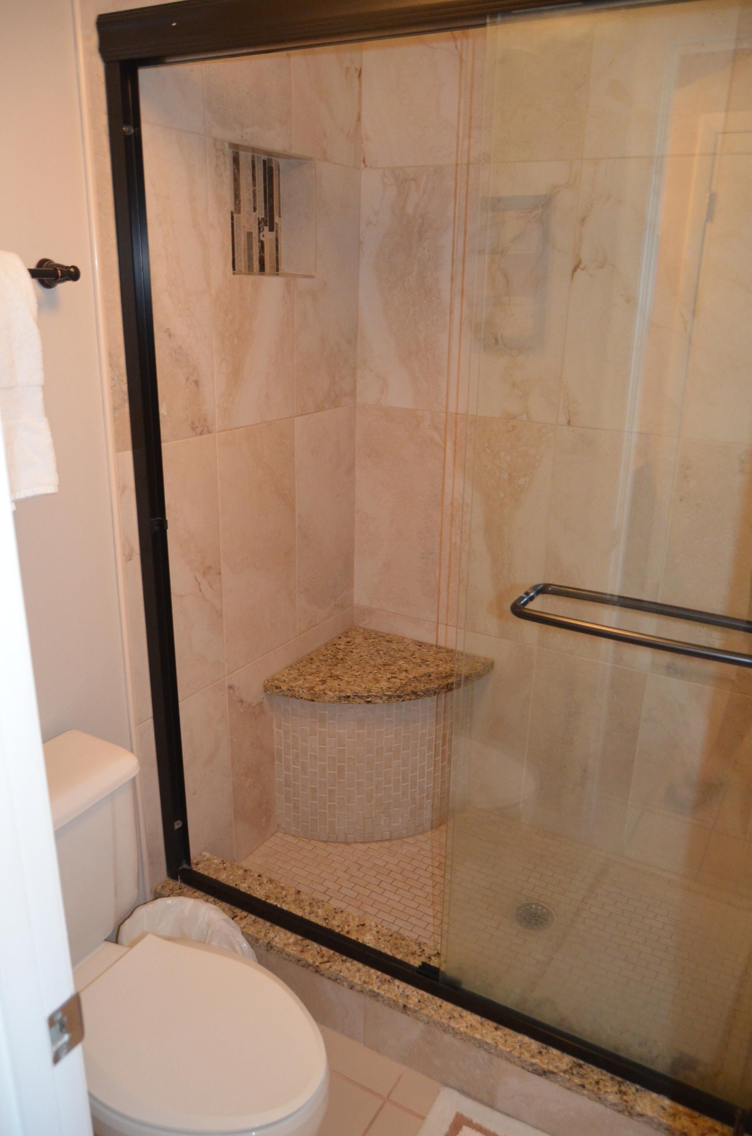 A bathroom with a glass-enclosed shower, a white toilet, and a tiled floor.
