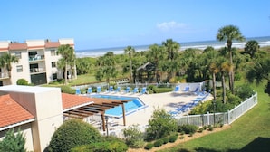 Um resort com área de piscina, cadeiras de praia e vista para o oceano.