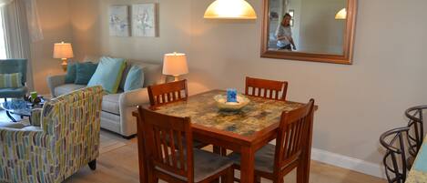 A dining area with a wooden table and chairs, a sofa, and a patterned armchair.