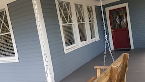 A porch with a swing, a red door, and white-framed windows. - Historic 1908 Downtown Home - Porch Swings - Mountain Views - Very Walkable (Asheville)