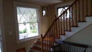 A staircase with wooden railings and a view of a garden through a window. - Historic 1908 Downtown Home - Porch Swings - Mountain Views - Very Walkable (Asheville)