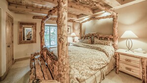 Camera da letto rustica con un grande letto, travi in legno e un camino in pietra.