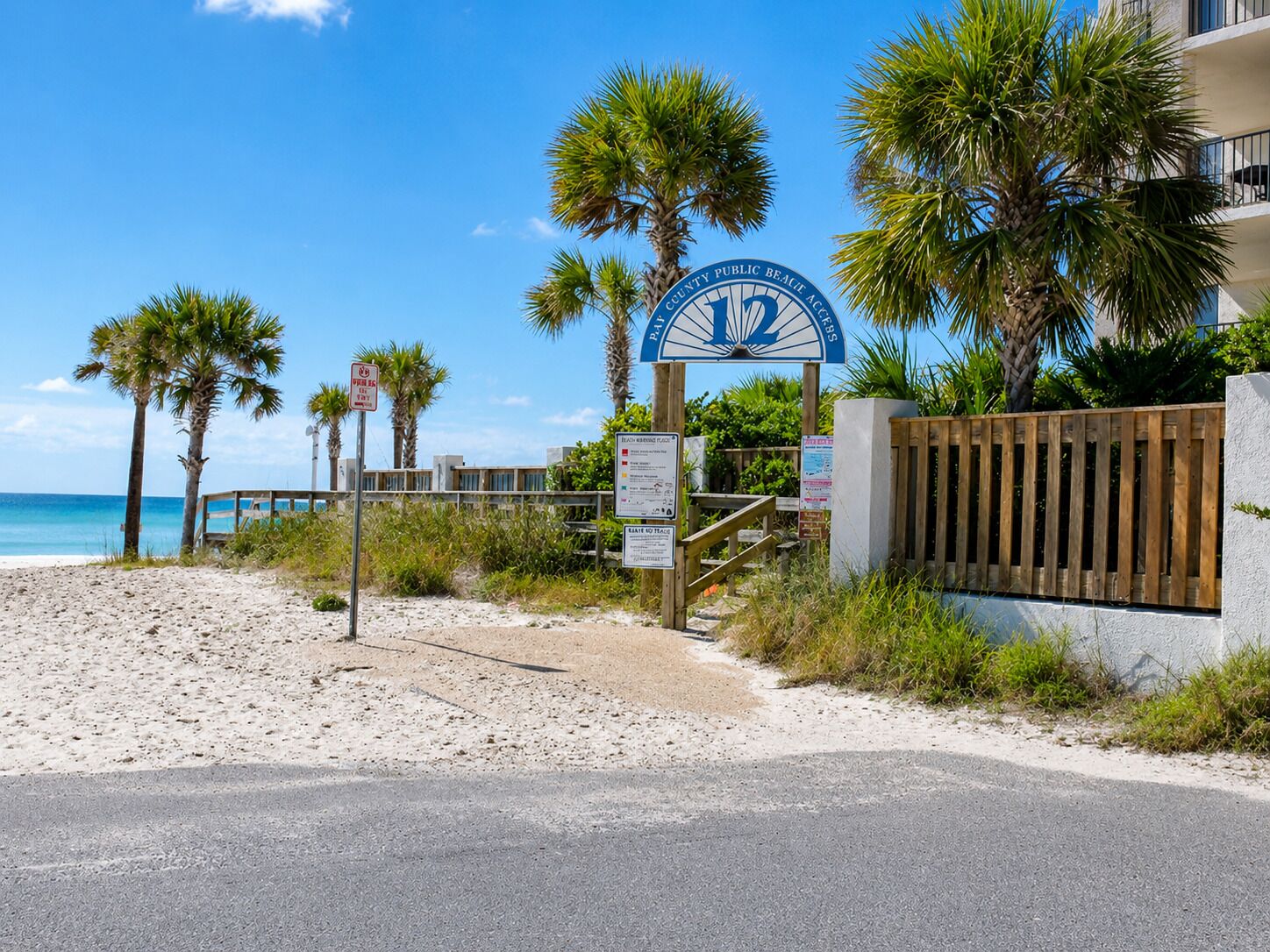 Une propriété située en bord de mer, avec un panneau indiquant un point d’accès public à la plage, une clôture en bois et une vue dégagée sur l’océan.