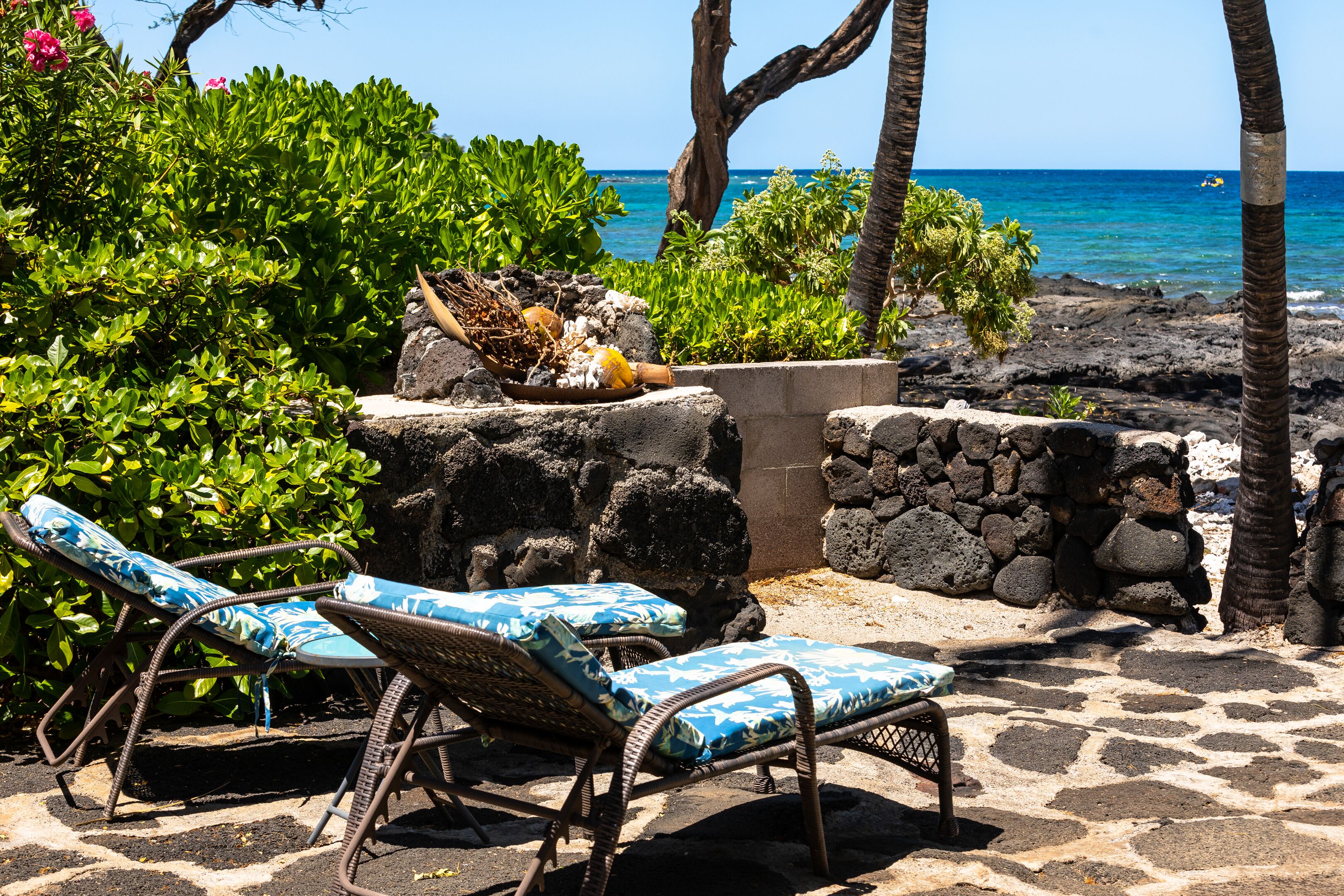 A stone pathway leading to a seating area with wicker chairs and a table with a decorative centerpiece.