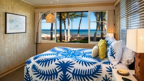 A hotel room with a large bed, a view of the beach, and a window with palm trees. - 'My Favorite Place on Earth' (Kamuela)
