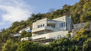 Un edifici de diverses plantes amb balcons, envoltat de verdura exuberant.