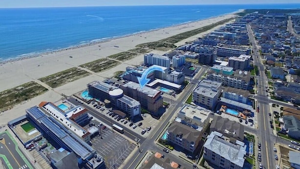 Vista aérea de una ciudad costera con playa, edificios altos y un estacionamiento.