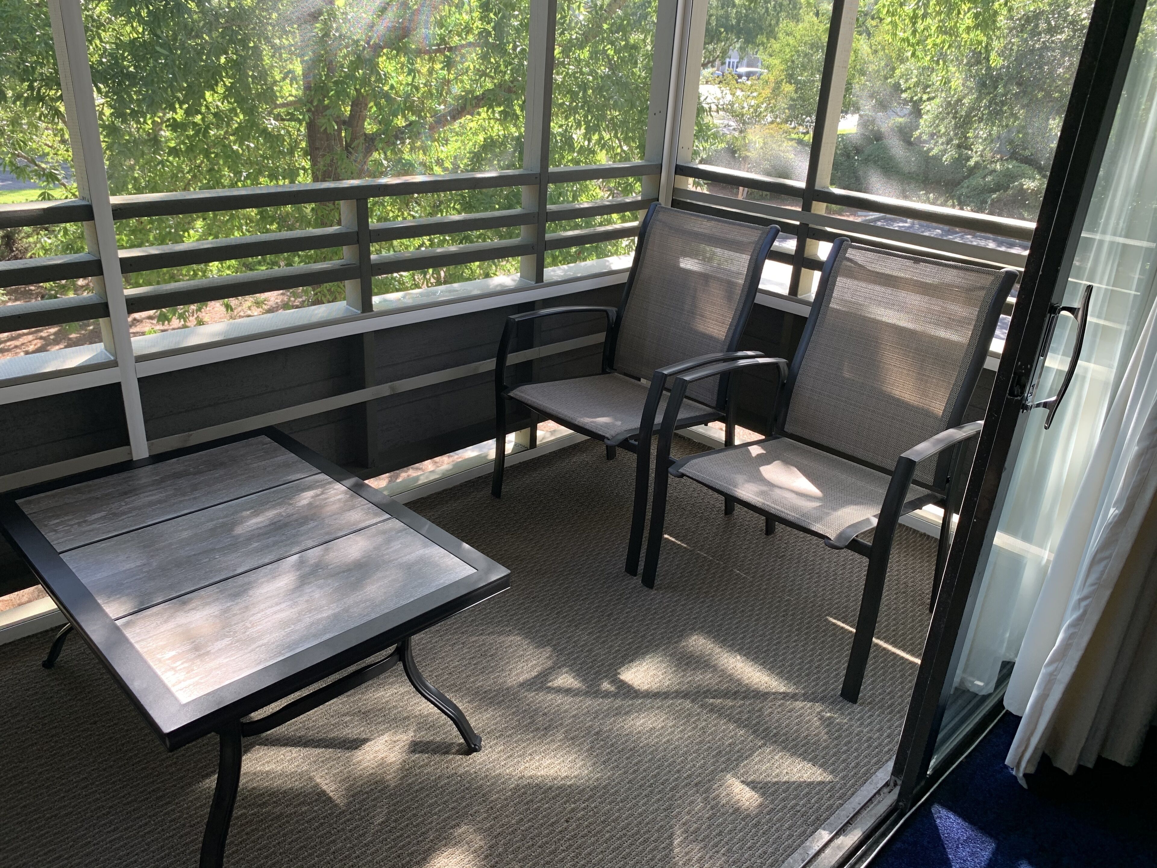 Ein überdachter Patio-Bereich mit Tisch und zwei Stühlen.