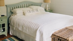 Een slaapkamer met een bed, een plafondventilator, een raam en een decoratief object aan de muur.