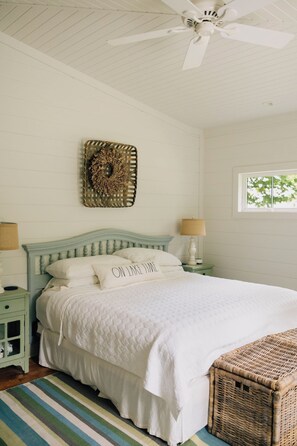 A bedroom with a bed, a ceiling fan, a window, and a wall-mounted decorative piece. - Lake Erie Lakefront Custom Built Cottage ~ Amazing Sunsets ~ Private!   (North East)