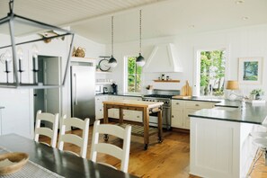Eine moderne Küche mit weißen Schränken, einer zentralen Kochinsel und einem Essbereich mit Tisch und Stühlen.