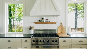 A kitchen with a stainless steel stove, wooden countertop, and white cabinetry.