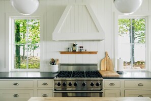 A kitchen with a stainless steel stove, wooden countertop, and white cabinetry. - Lake Erie Lakefront Custom Built Cottage ~ Amazing Sunsets ~ Private!   (North East)
