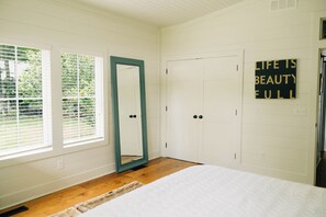 A bedroom with a bed, a door, a window with blinds, and a wall-mounted sign. - Lake Erie Lakefront Custom Built Cottage ~ Amazing Sunsets ~ Private! (North East)