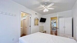 A bedroom with a bed, a ceiling fan, a TV, a wardrobe, and a bathroom visible through an open door. - Beautiful Bayside Gem Accepting 3 Night Stays! (Wildwood)