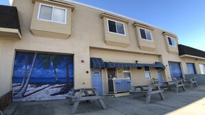 A multi-story building with a beige exterior, numbered units, and a blue garage door. - Beautiful Bayside Gem Accepting 3 Night Stays! (Wildwood)