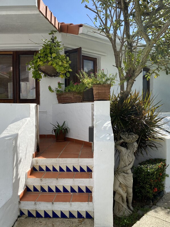 A white building with a tiled staircase leading to a door, surrounded by potted plants and a tree. - Mediterranean-Style Villa by Wyndham Resort, Beaches and Pools (Rio Grande)