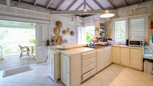A kitchen with a large island, white cabinets, and a hanging light fixture. - Charming West Coast Cottage Near Beach (The Garden)