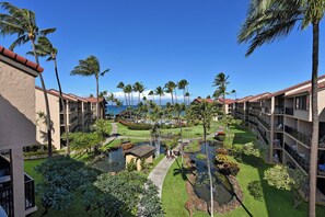 A resort with multiple-story buildings, a central courtyard with a water feature, and a view of the ocean.
