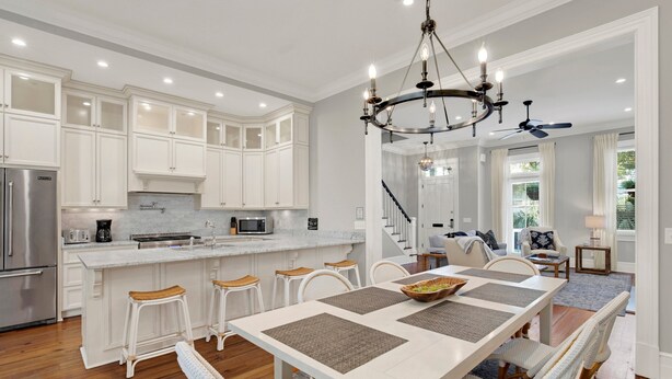 A spacious kitchen with white cabinets, a central island, and a dining area with a large table and chairs. - Heated Pool Access | 5*Clean | Flex Cancelation (Savannah)