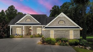 A two-story house with a stone facade, a front porch, and a driveway.
