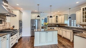 A spacious kitchen with white cabinetry, granite countertops, and a central island.