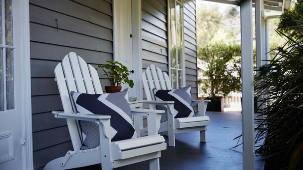 Two Adirondack chairs with striped cushions on a porch with white siding. - Inglenook Cottage Healesville (Healesville)